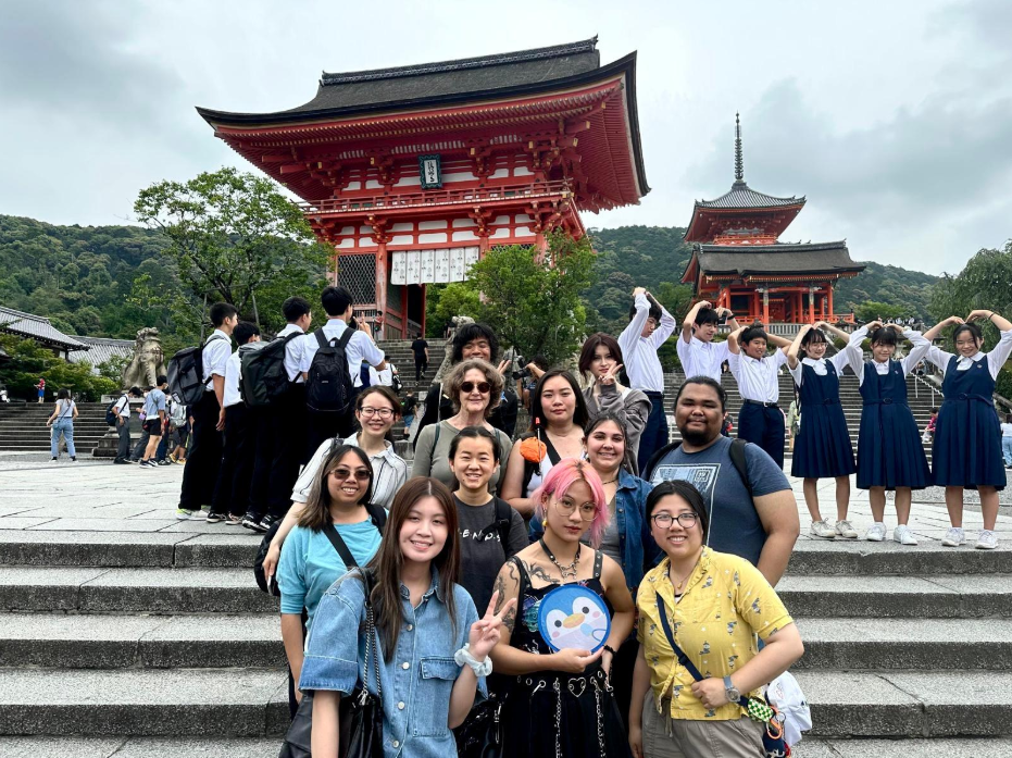 A diverse group of people poses for a picture in front of a beautifully detailed temple structure.